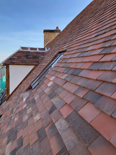 Versant de toiture rénové en tuiles plates de Bourgogne avec noue, lucarne et souche de cheminée